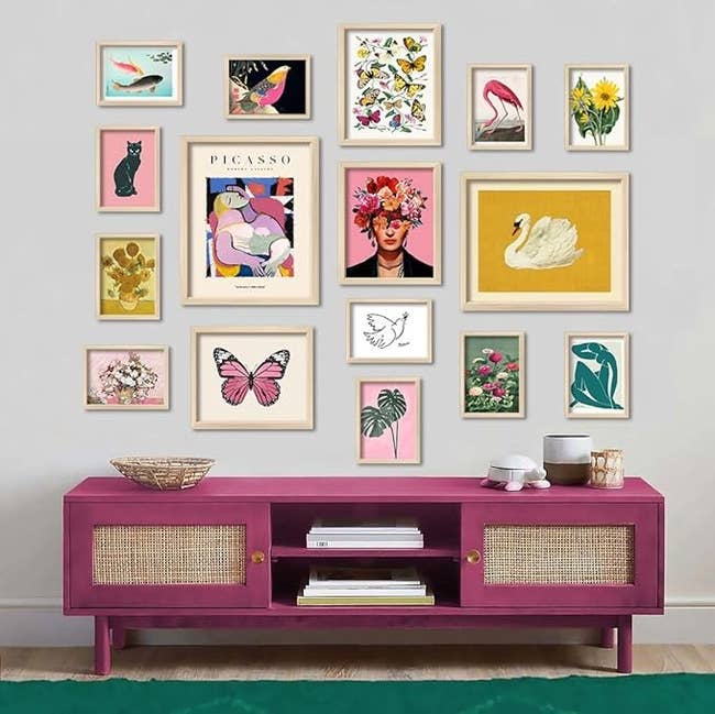 Artwork gallery wall above a magenta console table showcasing various framed prints with floral and animal motifs