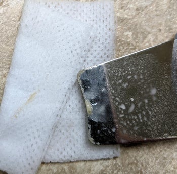 Reviewer's scraper after being used, showing the dirt and oil removed from skin