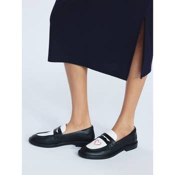 Black and white loafers with heart detail paired with a long skirt