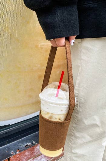 person holding a drink using the canvas bag holder