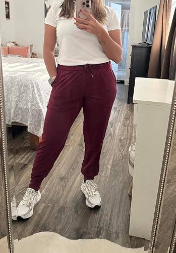 Person successful casual outfit with a achromatic t-shirt and jogger pants takes a reflector selfie successful a bedroom, showcasing comfy style