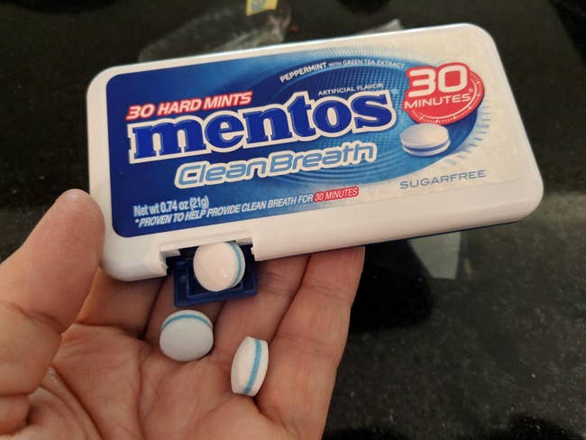 a reviewer holding a box of mentos clean breath mints