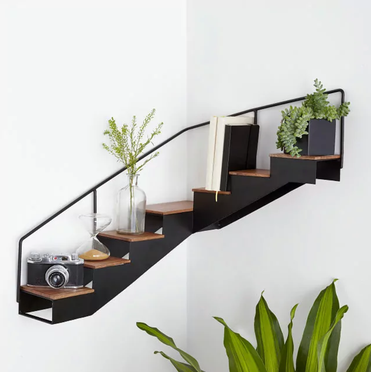 Black and brown floating staircase shelf with plants and decor on top