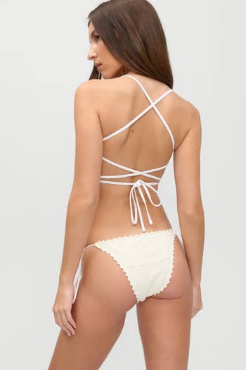 Woman in halter bikini with criss-cross back ties, showcasing swimwear style from behind in a shopping context