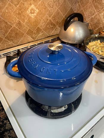blue dutch oven sitting connected a stove