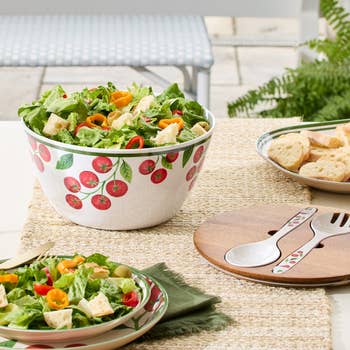 A acceptable   of fruit-patterned crockery   bowls and serving utensils, with caller  crockery   and breadstuff  arranged connected  a woven placemat, perfect  for outdoor dining