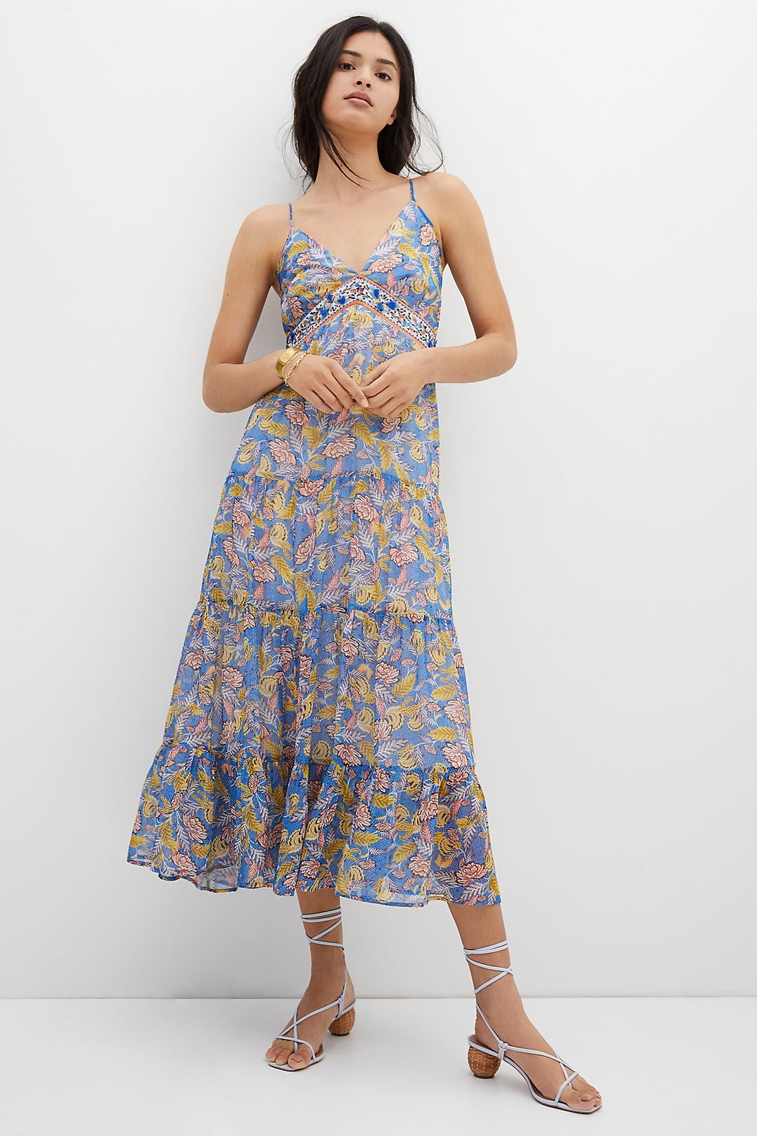 Model wearing light blue tiered maxi dress with yellow and pink leaves on it
