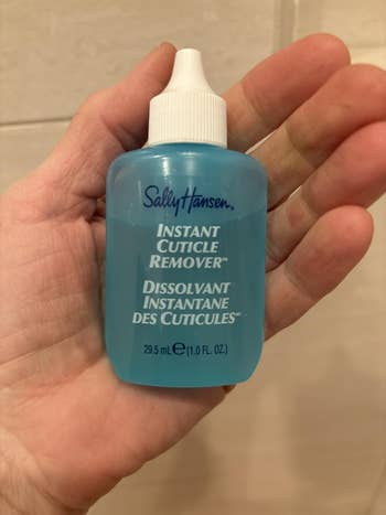 Person holding a vessel  of Sally Hansen Instant Cuticle Remover