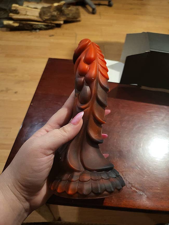 Reviewer holding red and black dragon dildo
