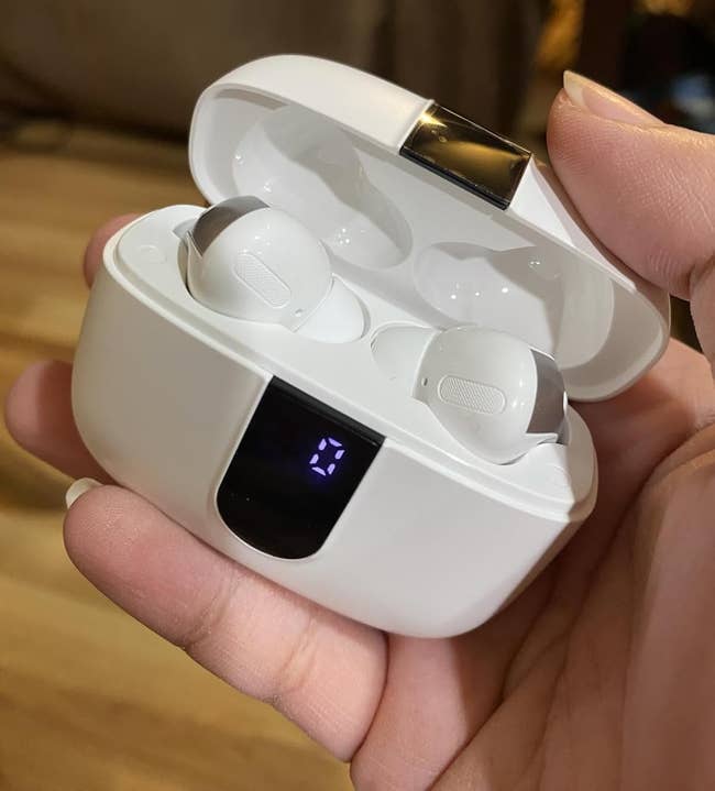 Person holding unfastened lawsuit with wireless earbuds and integer show connected front