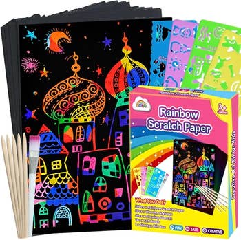 The scratch art kit shown with black paper featuring a colorful drawing, wooden sticks, and stencils 