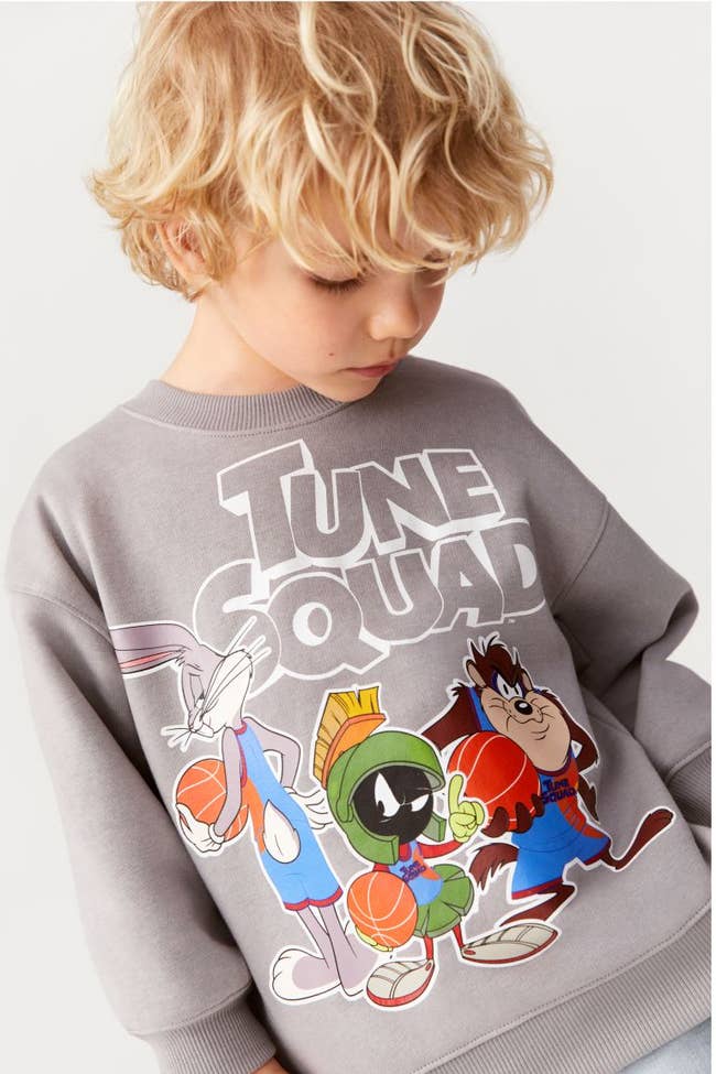 a child model in a gray sweatshirt with bugs bunny and the tune squad on it