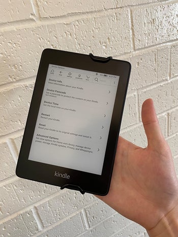 reviewer showing the front of the Kindle and how easy it is to hold a Kindle with the strap