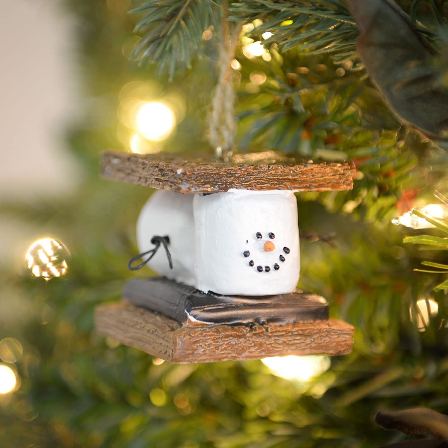 an ornament of a s'more with a smiley face snowman marshmallow
