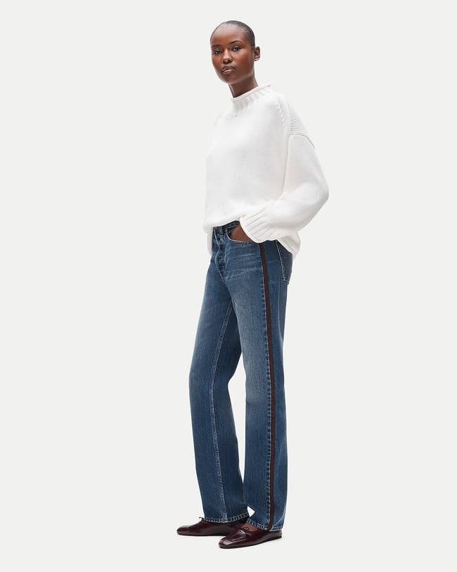 Person successful  a cozy sweater, consecutive  jeans with broadside  stripes, and loafers. Pose is casual; outfit stylish and relaxed