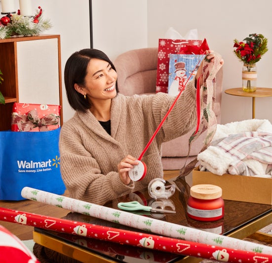 Rie holds out ribbon above table with wrapping