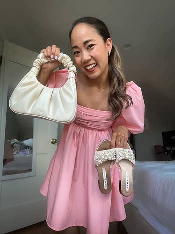 reviewer in a puff pink sleeve dress holding the same JW Pei bag in a white color