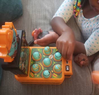 Child playing with a artifact resembling a whack-a-mole crippled connected a couch