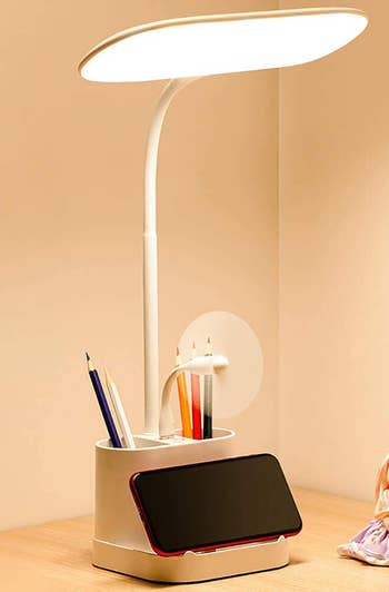 the office lamp holding a phone at its base and pens in its holder