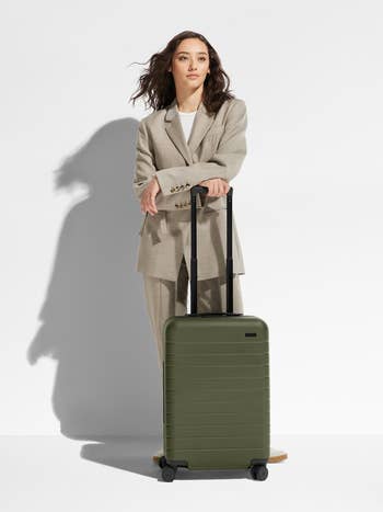 A model posing with the green suitcase