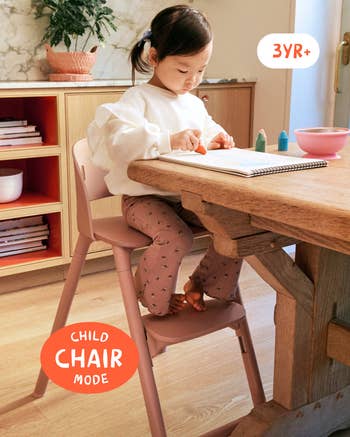 Child sitting astatine  a array  connected  a pinkish  chair, drafting  with crayons. The seat  is labeled for children aged 3 years and up