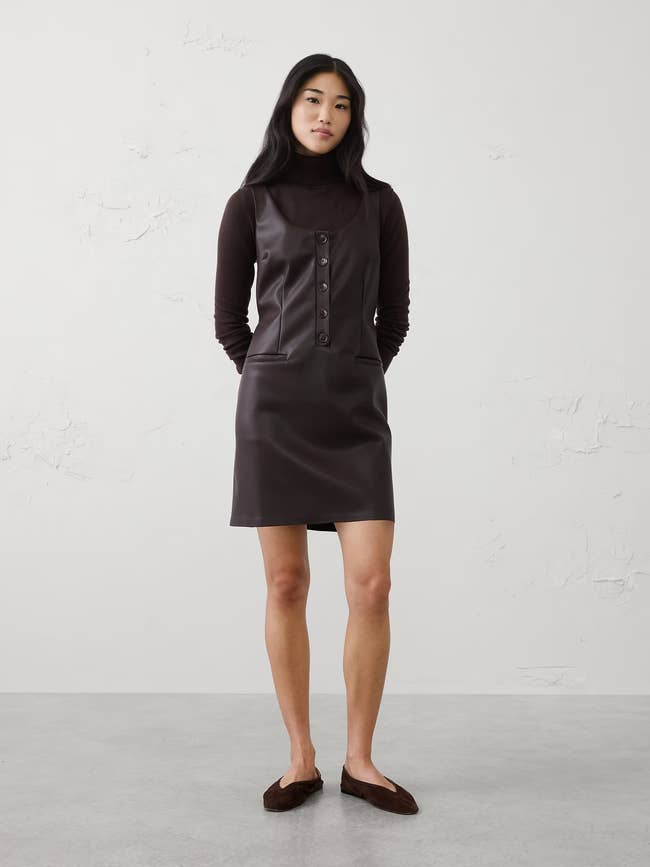 Person wearing a chic, minimalist sleeveless formal implicit a turtleneck, paired with flats, lasting connected a neutral background