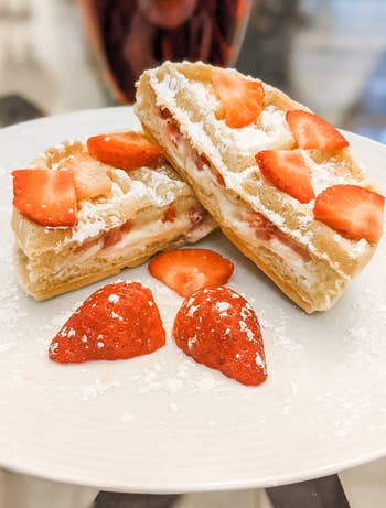 plate with strawberry cream puff pastry, dusted with powdered sugar, accompanied by fresh strawberry slices