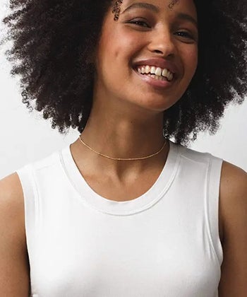 a model wearing a gold satellite chain with a white tank top