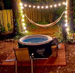 the hot tub in a backyard lit by fairy lights