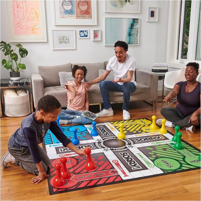 Family of four playing a large floor version of Sorry! game
