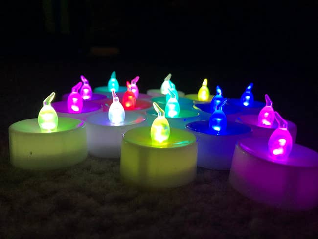 Reviewer image of flameless tea light candles grouped together and lit in yellow, blue, purple, and red colors
