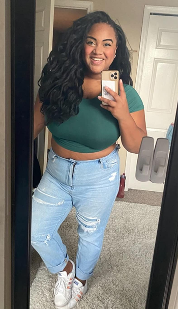 reviewer wearing the green tee with jeans and white sneakers