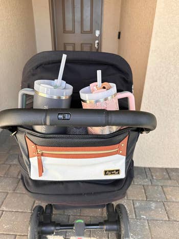 A black baby stroller with a storage compartment and two drinks in cup holders