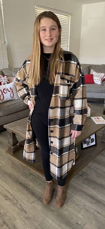 Person successful  a plaid, knee-length overgarment  and achromatic  outfit stands successful  a cozy surviving  country   with vacation  decor