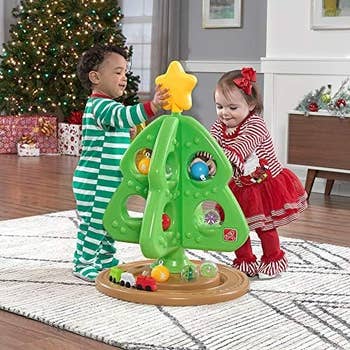 toddlers playing with a plastic toy christmas tree