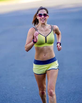 Person moving  outdoors successful  diversion  wear, including a sports bra and shorts, with a focused expression. They are wearing sunglasses and a wristwatch