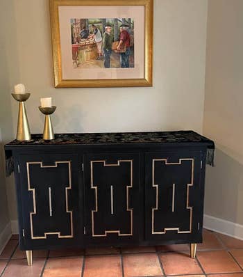 tapered brass metal legs supporting a black cabinet