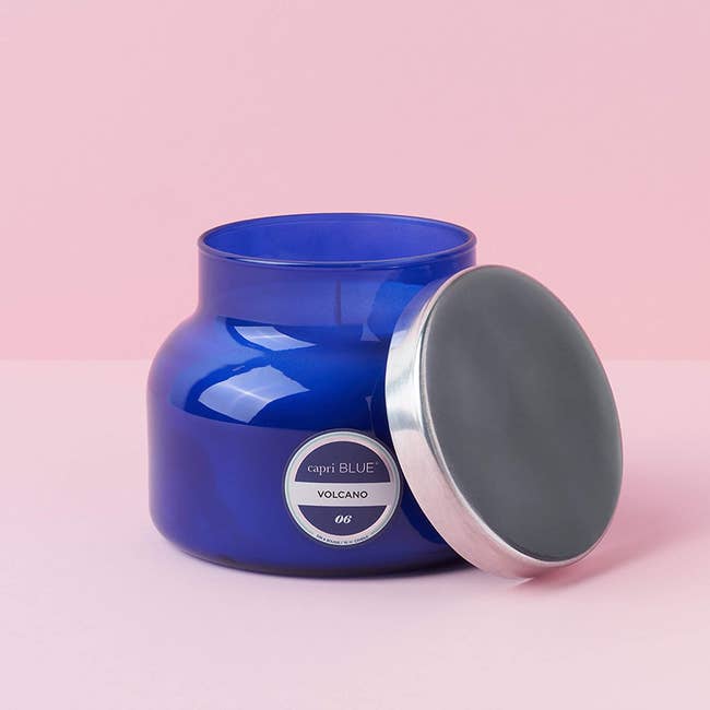 capri blue volcano candle in a blue glass jar with the tin lid off