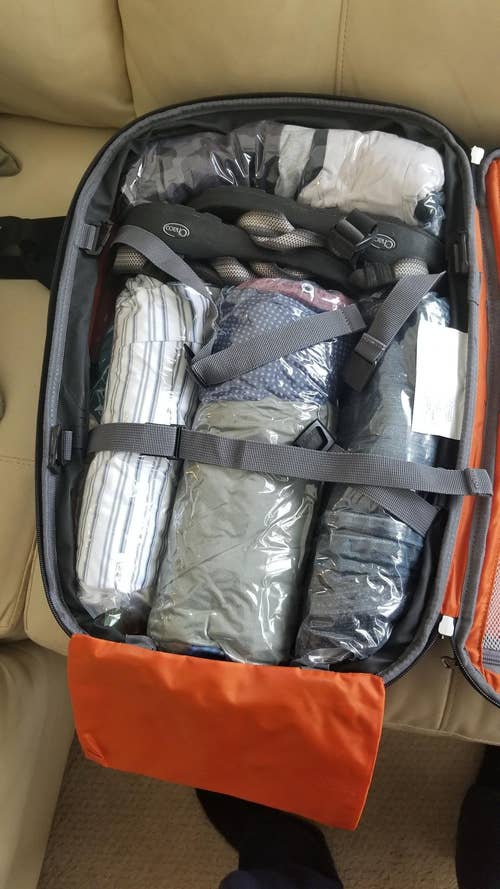 Open suitcase packed with clothes in compression space saver bags