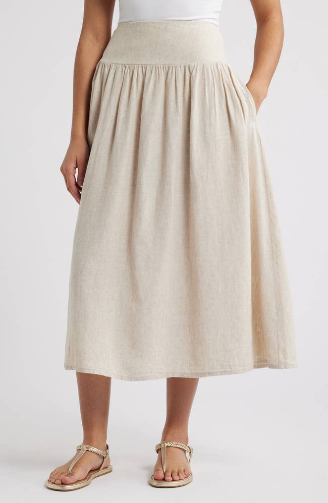 model wearing an ankle-length, high-waisted skirt with a escaped fit, paired with sandals. Suitable for casual and summertime styles