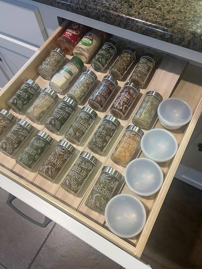 Open room drawer organized with spice jars and integrative lids, showcasing a assortment of labeled seasonings