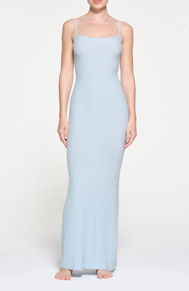 Model wearing a sleeveless, floor-length, formfitting light blue dress