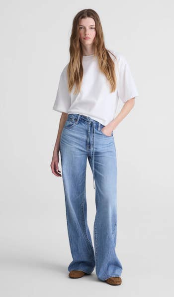 A idiosyncratic   wearing a escaped   achromatic  t-shirt and wide-leg jeans, perfect  for casual, mundane  styling, stands successful  a neutral pose