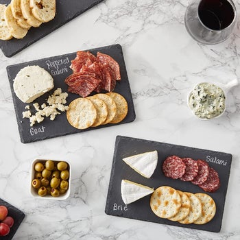 black mini cheese boards with cheeses and meats labeled in chalk