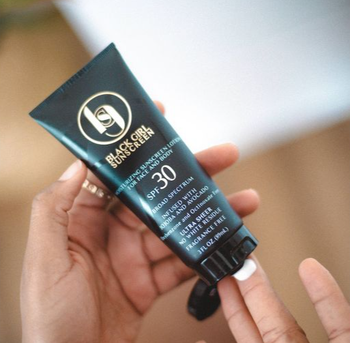 hands squeezing sunscreen out of tube