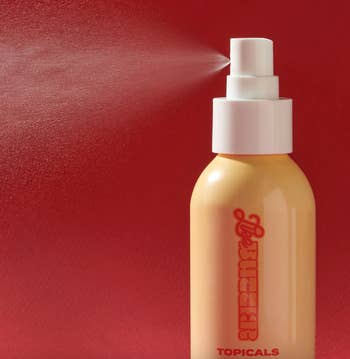 Bottle of Topicals skincare spray against a red background