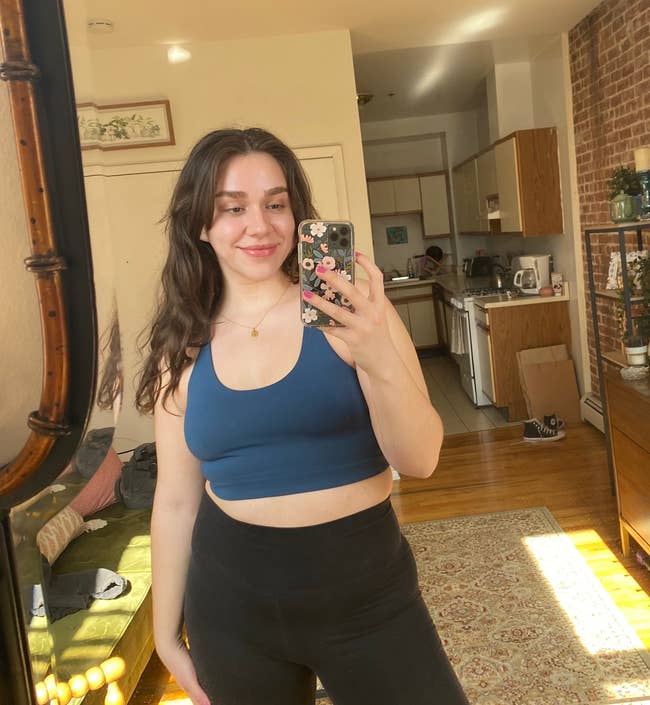 BuzzFeed writer Clara McMahon in dark blue halter sports bra and black leggings