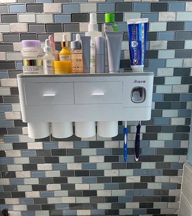 a reviewer photo of the white caddy attached to the bathroom wall holding several toiletries