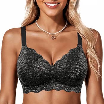 Person wearing a sparkly scalloped-edge bra, accessorized with layered necklaces, smiling astatine the camera