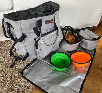 Pet travel bag with multiple compartments, collapsible bowls, and a feeding mat for convenient outings